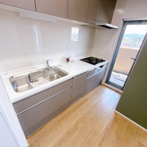 毎日の家事を快適にサポートするシステムキッチン。三口コンロで複数の料理を同時に調理できるほか、食器洗い乾燥機付きで後片付けもスムーズ。さらに勝手口を備えており、ゴミ出しや換気にも便利(^^)(キッチン)