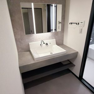 洗練されたグレーの洗面カウンターが印象的なパウダールーム。洗面鏡やオープン収納を備え、毎日の身支度も快適に行えます(内装)